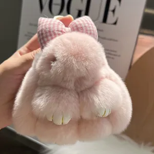 Close-up of pink rabbit plush keychain with checkered bow and detailed gold-stitched paws