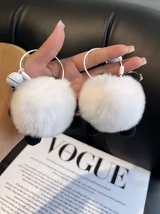 Close-up of fluffy panda fur keychains with bells held in hand for size display
