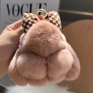 Detailed macro view of soft pink plush keychain with checkered bow and gold clasp