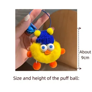 Detail of yellow plush duck keychain with blue knitted hat and bell, measuring 9cm height