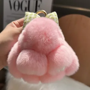 Detail of pink fluffy bunny keychain with a green plaid bow and golden metal ring