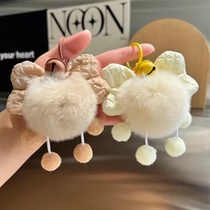 Close-up of soft faux fur pompom charms with bowknot and bell for bags and keys