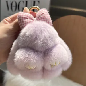 Macro shot of purple plush rabbit keychain with pink bow and golden metal ring detail