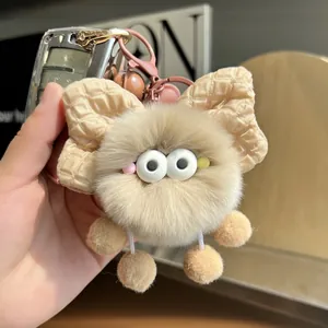 Detailed close-up of khaki plush soot sprite charm with checkered bow and pink clasp