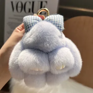 Plush light blue rabbit keychain with gingham bow and golden ring on fuzzy background