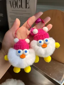 Nahaufnahme von süßen Enten-Plüschanhängern mit rosa Strickmützen und lila Glöckchen