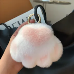 Detailed close-up of a plush cat paw keychain with soft fur and pink heart pads