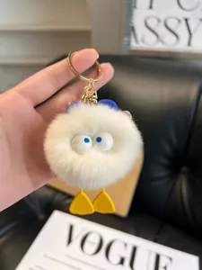 Cute white plush duck keychain with large blue eyes and golden metal clip on bag