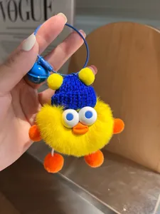 Detail eines gelben Enten-Plüschanhängers mit blauer Strickmütze und kleinem Glöckchen