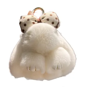 Cute white plush bunny keychain with polka dot bow and golden ring on white background