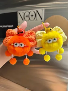 Detail of plush monster keychains in orange and yellow with fluffy fur and bow accents