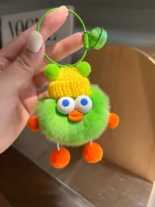 Makro-Detail des grünen Plüsch-Monsters mit gelber Strickmütze und orangefarbenen Pompons