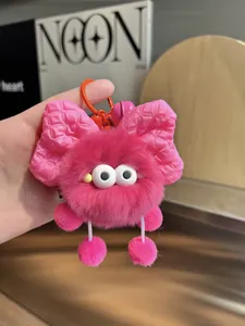 Detailed view of plush pink pompom keychain with oversized bow and small pink bell