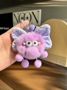 Detail of purple plush soot sprite keychain with rabbit ears and bell on hand