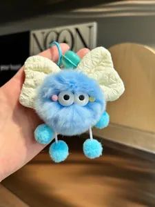 Detail view of a blue furry soot sprite keychain with a white fabric bow.