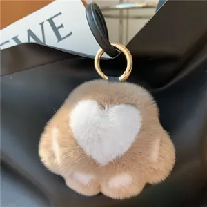 Close-up of a cute plush cat paw bag charm with heart detail on a black bag