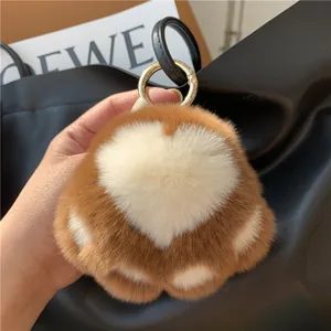 Close-up of cat paw plush keychain with white heart pattern and gold ring on black bag