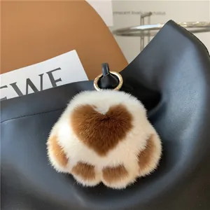 Detailed plush cat paw keychain with cream fur and brown heart pattern on a bag
