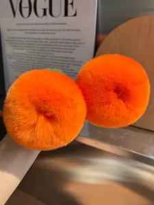 Dettaglio ravvicinato di pompon in pelliccia sintetica arancione con trama morbida