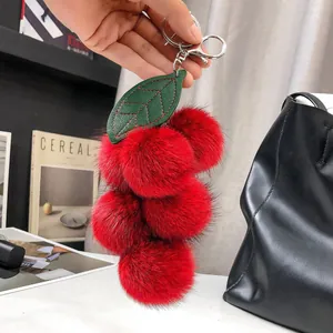 Dettaglio charm borsa ciliegia in pelliccia di volpe con foglia in pelle e portachiavi argento
