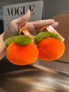 Dettaglio di portachiavi a forma di cachi in morbido peluche arancione con ganci