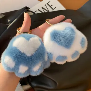 Detail of plush cat paw keychains in white and blue fur with golden metal rings
