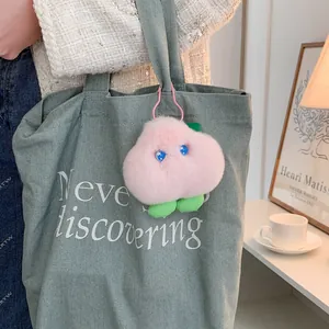 Pink plush monster keychain with star eyes on green canvas bag for stylish bag decor