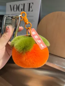 Dettaglio portachiavi a forma di cachi in peluche con pelliccia sintetica e foglia verde