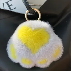 Macro view of heart-shaped plush cat paw charm with yellow spots and golden metal ring