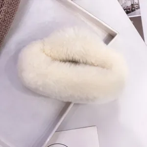 Detail shot of a plush cream faux fur hair claw clip resting on a white display tray