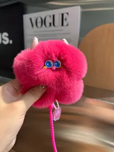 Dettaglio del portachiavi mostro rosa peloso con occhi blu e pendente a cuore