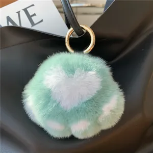 Fluffy mint green rabbit fur kitten paw keychain on a black leather handbag