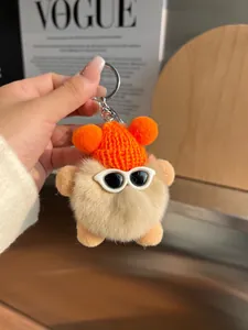 Détail macro du porte-clés en peluche avec bonnet orange et lunettes sur revue Vogue