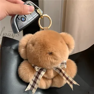Close-up of brown plush bear pendant with checkered bow tie and gold metal ring