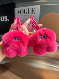 Dettaglio di portachiavi mostro in ecopelliccia rosa con occhi e targhette a cuore