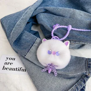 Cute white plush cat keychain with purple sequin eyes and checkered bow on denim fabric