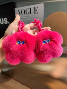 Dettaglio di due portachiavi mostro in peluche fucsia con grandi occhi blu e catena
