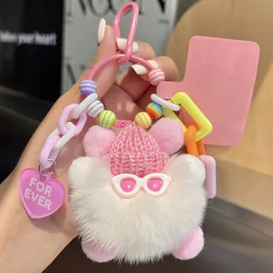 Detail of pink plush bear keychain with colorful beads and knitted hat on a Vogue background
