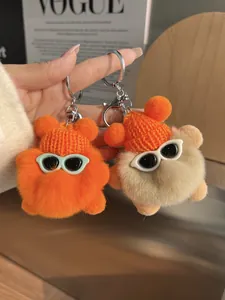 Détail de porte-clés en peluche avec bonnets en tricot et lunettes de soleil orange et beige