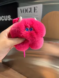 Dettaglio macro di un portachiavi mostro in peluche rosa con occhi a cuore blu