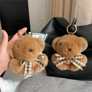 Detailed close-up of a brown fluffy rabbit fur bear keychain hanging on a black leather bag