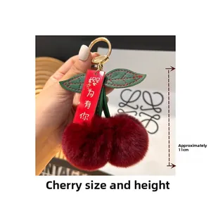 Detail of plush cherry keychain with soft red faux fur balls and green leather leaves