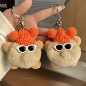 Gros plan sur deux porte-clés ours en peluche beige avec bonnets orange et lunettes
