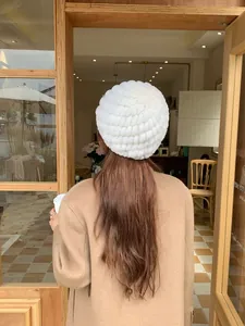 Thick white rabbit fur knitted beanie for winter warmth shown in a cozy outdoor scene