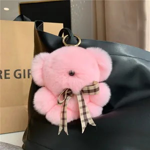 Pink rabbit fur bear keychain with brown plaid bow on a black leather bag