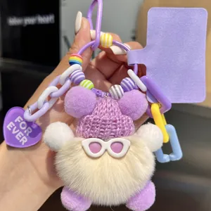 Close-up of plush ball keychain with purple knit hat, sunglasses, and decorative charms