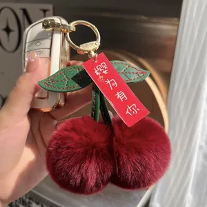Detailed close-up of handmade cherry plush keychain with soft faux rabbit fur and gold clasp