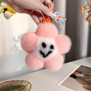 Dettaglio di un portachiavi a fiore in peluche rosa con viso sorridente e chiusura in metallo