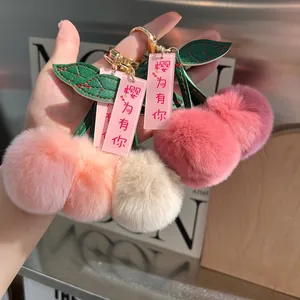 Close-up of plush cherry bag charms with soft faux rabbit fur and golden metal clasps