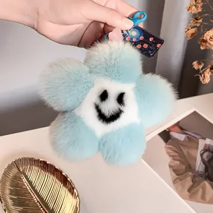 Dettaglio del portachiavi a fiore di peluche blu e bianco con faccina sorridente
